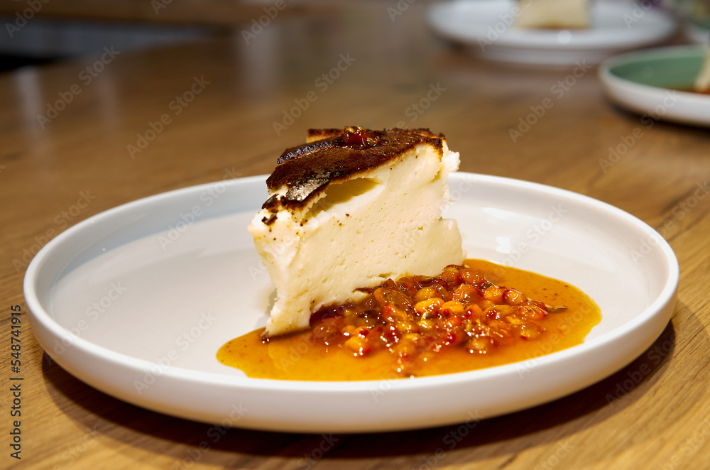 Piece of cheesecake with sea buckthorn jam on a plate Piece of cheesecake with sea buckthorn jam on a plate