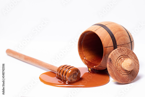 Dark honey flows from the barrel on a white background