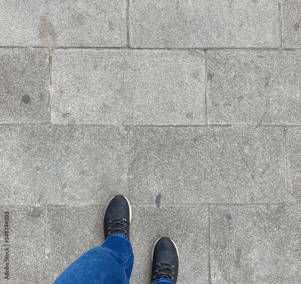 photo of her black shoes and blue jean standing on gray street tiles, at the beginning of autumn, in october november. hope and beauty of street lifestyle photo of her black shoes and blue jean standing on gray street tiles, at the beginning of autumn, in october november. hope and beauty of street lifestyle