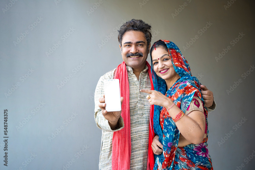 Happy Indian farmer couple showing smart phone.