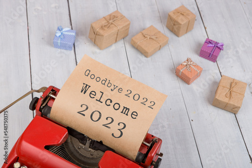 Holidays concept - red typewriter with text "Goodbye 2022 Welcome 2023", gift boxes