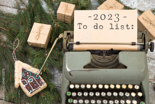 Typewriter with the inscription 2023 To do list, fir branches, gift boxes and gingerbread house