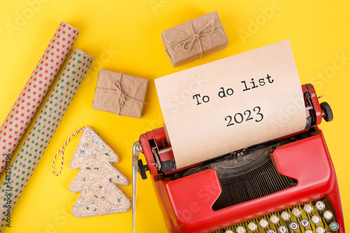 Holidays concept - red typewriter with text "To do list 2023", gift boxes and wrapping paper