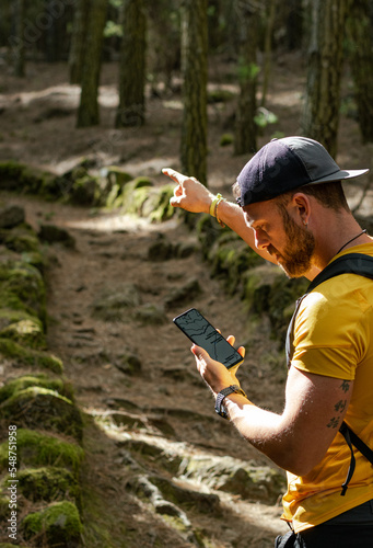 Persona masculina blanca con barba y gorra perdido mirando móvil con mapa o gps buscando el camino. photo