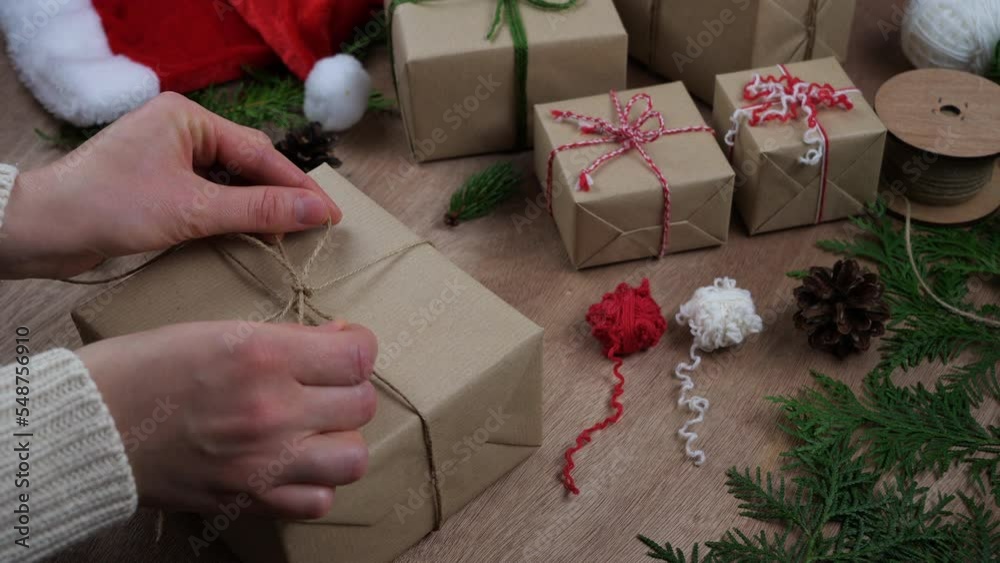 woman's hands preparing a gift box Christmas present using recycled wrapping paper