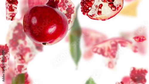 Pomegranate fruit pieces, slices and leaves being moved downwards isolated on white. Top view. Seamless looping. High quality 4k video.