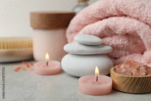 Beautiful composition with burning candles and different spa products on light grey table  closeup