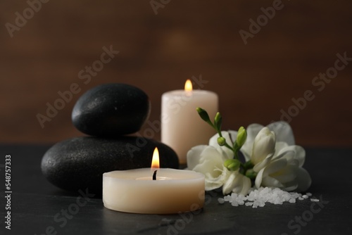 Beautiful composition with spa stones, burning candles and flowers on black table