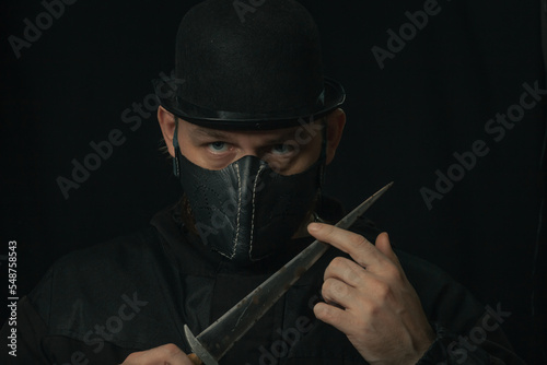 Scary man with knife or dagger creepy mask and hat in the dark