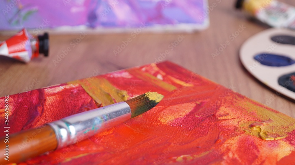 Artist's canvas with mixed paints and brush on wooden table, closeup