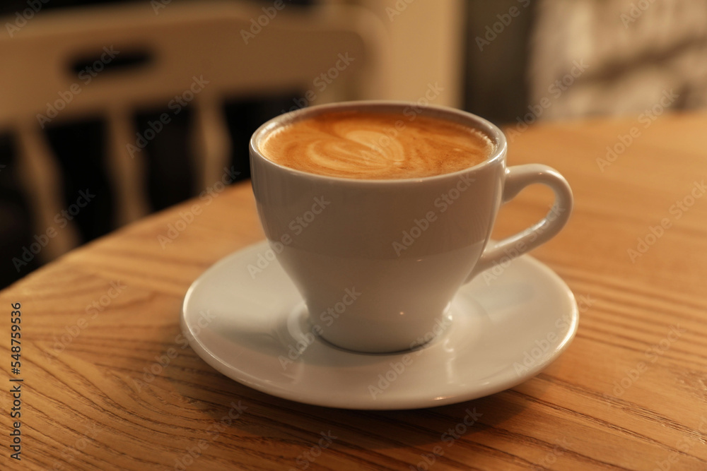 Cup of aromatic hot coffee on wooden table in cafe, closeup