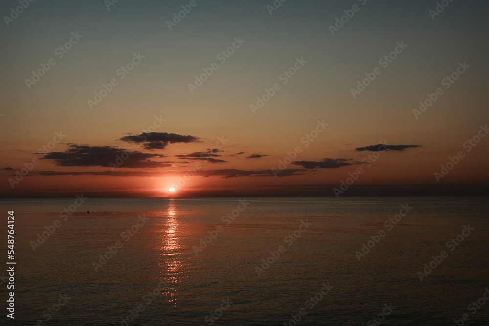 Waves on the sea during sunset. Relaxation, enjoyment. Journey to the ocean, peace and happiness. Colorful, bright, orange sunset. The sun shines through the clouds on the ocean. Beautiful wallpapers