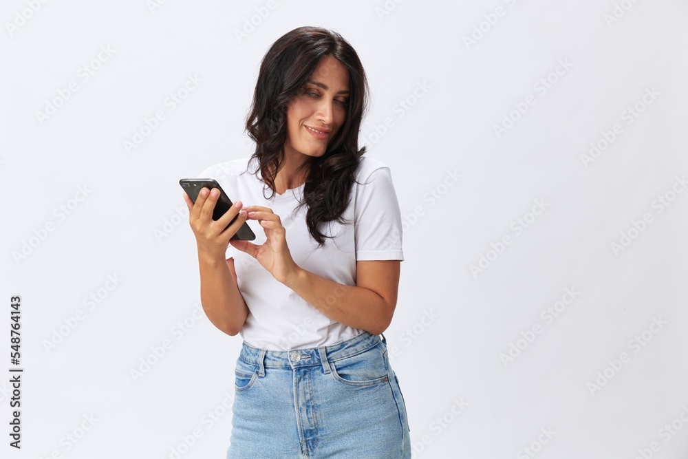 Woman blogger with a phone in her hands photo content, video call, selfie smile with teeth in a white t-shirt on a white background, copy space, emotions and gestures signals Woman blogger with a phone in her hands photo content, video call, selfie smile with teeth in a white t-shirt on a white background, copy space, emotions and gestures signals