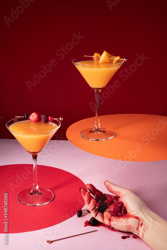 Scene of a drunken woman’s hand holding smashed berries with orange juice cocktails