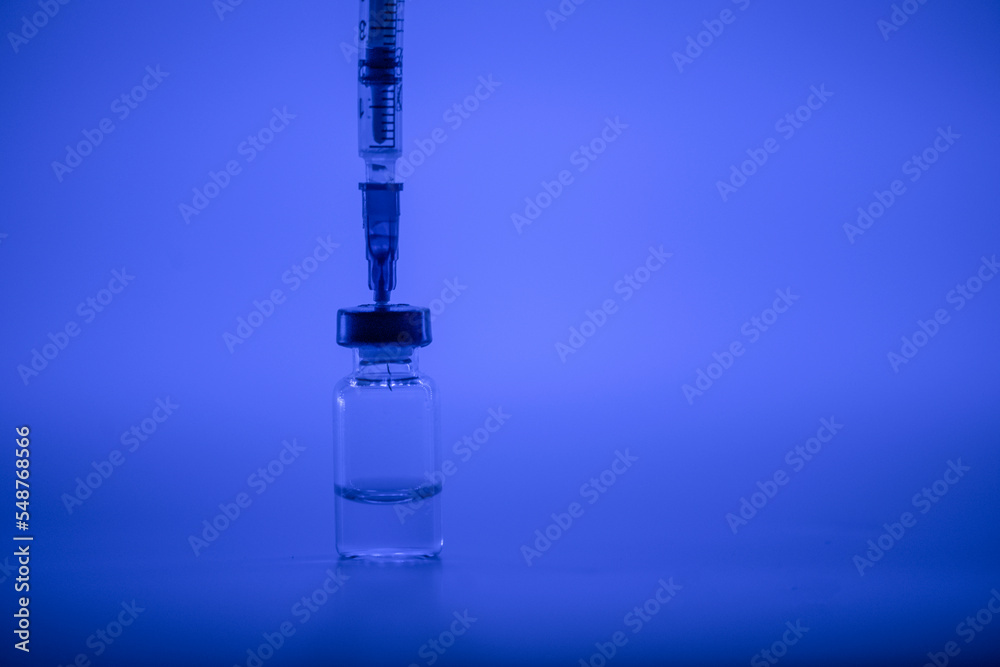 Vaccine vial, syringe with flu shot needle, vaccination medical concept, subcutaneous injection on blue background. Copy space. Test immunization and vaccination laboratory. Healthcare and medicine. Vaccine vial, syringe with flu shot needle, vaccination medical concept, subcutaneous injection on blue background. Copy space. Test immunization and vaccination laboratory. Healthcare and medicine.