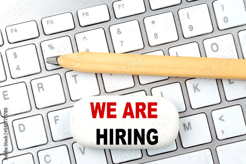 WE ARE HIRING text on eraser with pencil on keyboard