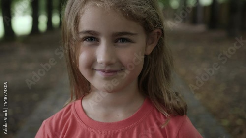 Portrait Smiling Little Girl Looking at Camera. Laughs Happily Child at Outdoors. Inquisitive Little Girl Portrait. Face Funny Contemplative Child. Laughing Cute Pretty Schoolgirl Elementary Student.
