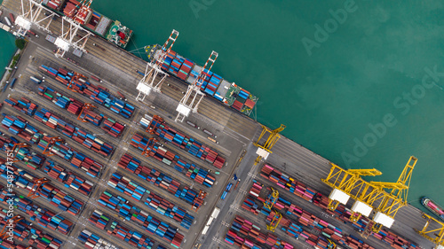 commercial port loading and unloading cargo from container ship import and export by crane for distributing goods by trailers transported to customers and dealers, aerial view