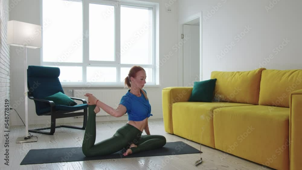 Adult skinny woman doing yoga exercises in the living room with smoldering incense on the floor Adult skinny woman doing yoga exercises in the living room with smoldering incense on the floor