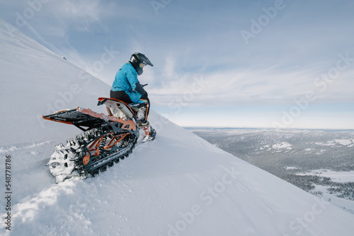 Snowbike rider on steep snowy slope. Modify motorcycle with ski and special snowmobile-style track instead of wheels