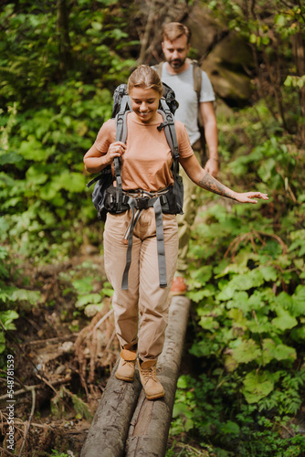 White young couple with backpacks hiking in green forest