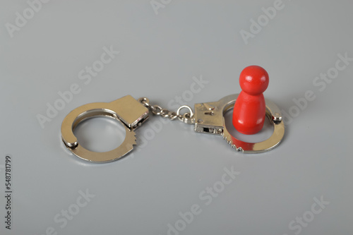 Red wooden people of figure with handcuff locked. Handcuffed convict, law offender and justice concept. photo