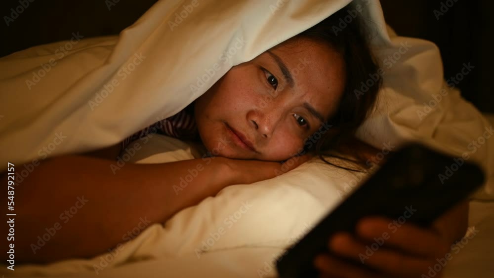 Asian woman playing game on smartphone in the bed at night,Thailand people,Addict social media Asian woman playing game on smartphone in the bed at night,Thailand people,Addict social media