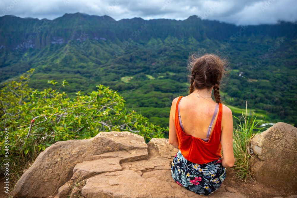 hiker girl stands at the top of olomana ridge trail admiring the panorama of oahu and hawaii mountains; famous three peaks on oahu, dangerous hiking on hawaii mountains, hawaii holidays