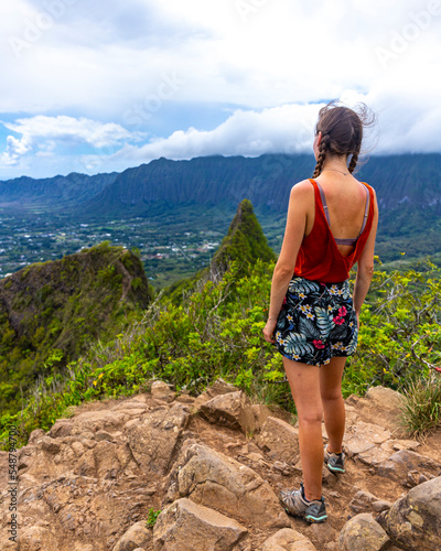 hiker girl stands at the top of olomana ridge trail admiring the panorama of oahu and hawaii mountains; famous three peaks on oahu, dangerous hiking on hawaii mountains, hawaii holidays photo