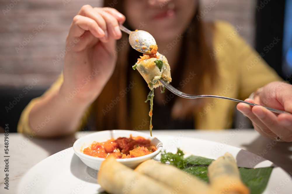 woman eating spinach spring roll served with tomato salsa food in a restaurant