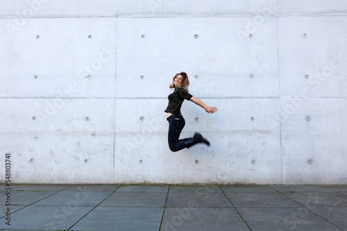 woman in black clothes jumping in front of grey wall