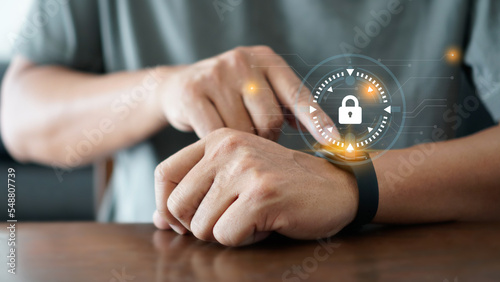 Image of a man's hand inspecting a digital wristwatch network security. Holographic security symbol displayed on digital wristwatch. Data technology and security network concept