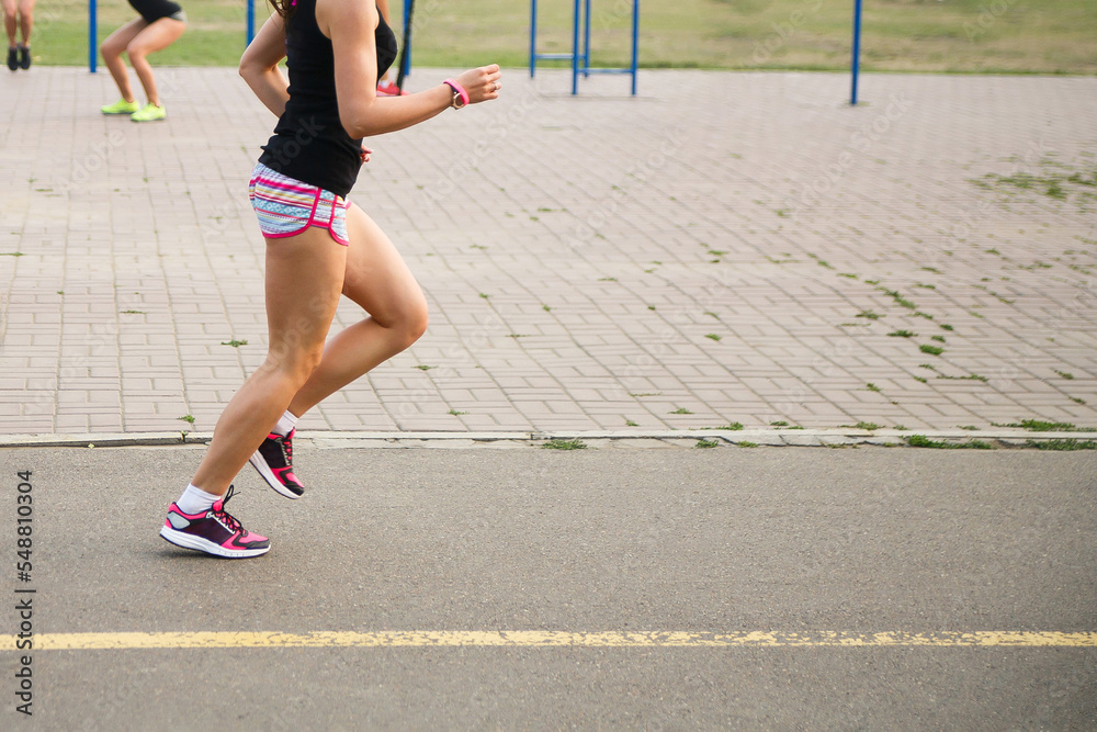 The woman runs along the road. Athletic woman runner trains on the sports ground