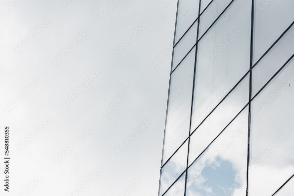 Close up to a skyscraper exterior front side full of windows in which clouds are reflected Close up to a skyscraper exterior front side full of windows in which clouds are reflected