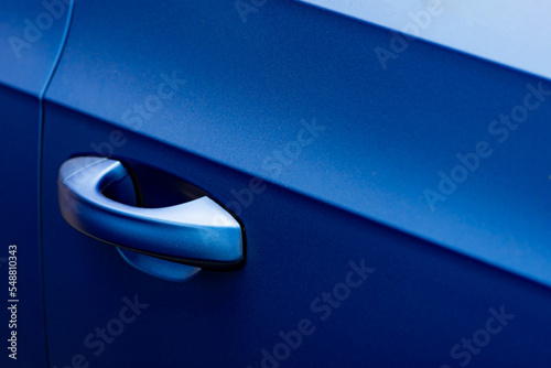 Close up to a metallic blue car door handle with shine