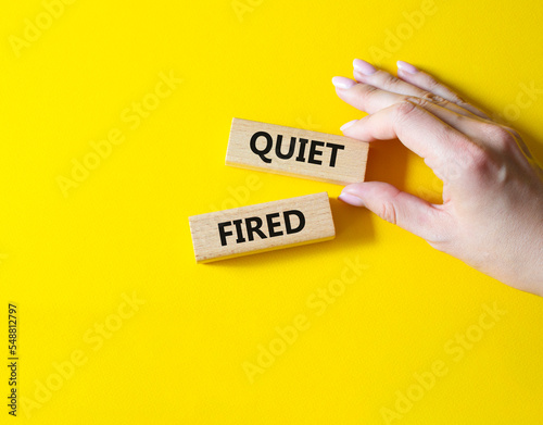 Quiet fired symbol. Concept word Quiet fired on wooden blocks. Businessman hand. Beautiful yellow background. Business and Quiet fired concept. Copy space