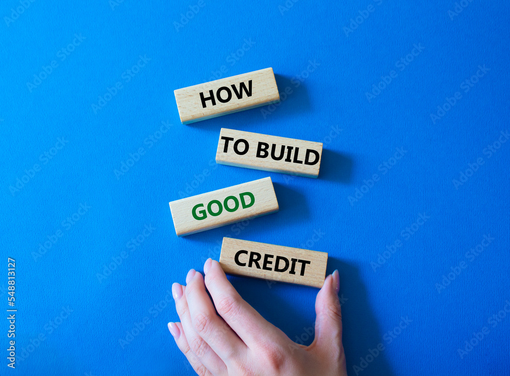 How to build good credit symbol. Concept words How to build good credit on wooden blocks. Beautiful blue background. Businessman hand. Business and How to build good credit concept. Copy space.