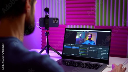 A young blogger streams an online video broadcast from his phone in his home studio photo