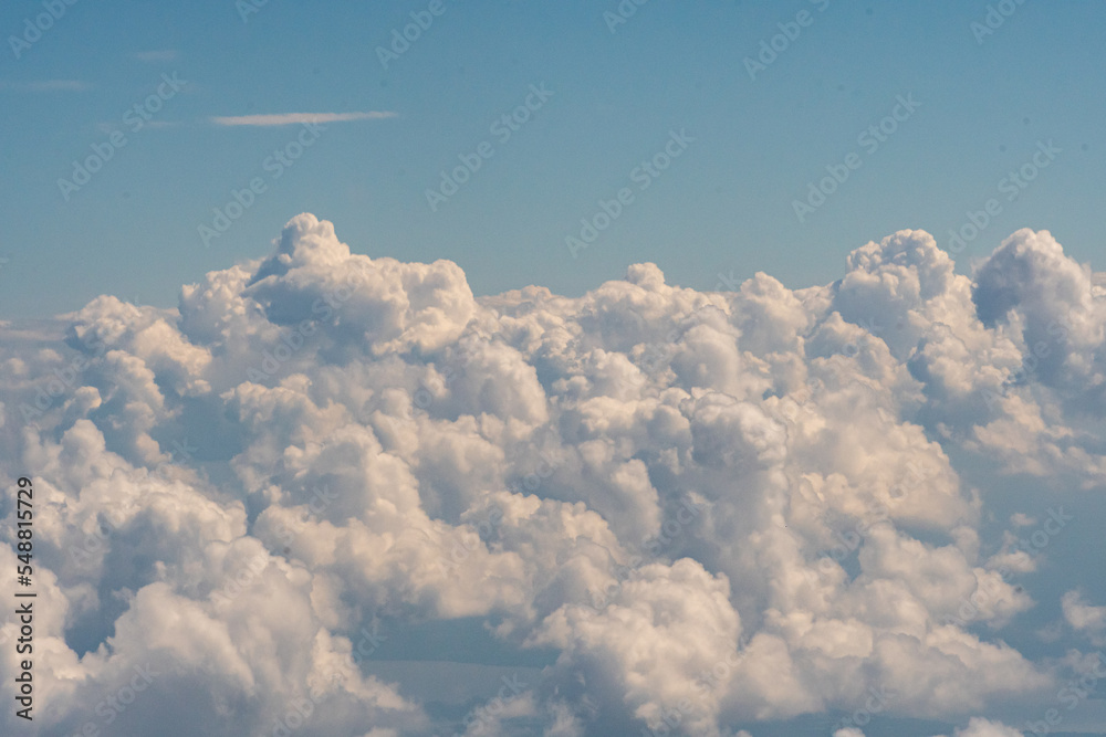 Fototapeta premium Aerial view of puffy white clouds from an airplane window at a comfortable cruising altitude 