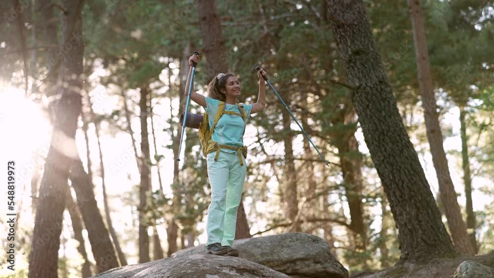 caucasian woman on a rock in the forest is trekking with a backpack