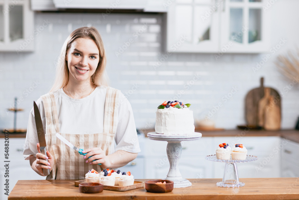 Pastry chef confectioner young caucasian woman with knife cut slice cake on kitchen table. Cakes cupcakes and sweet dessert Pastry chef confectioner young caucasian woman with knife cut slice cake on kitchen table. Cakes cupcakes and sweet dessert