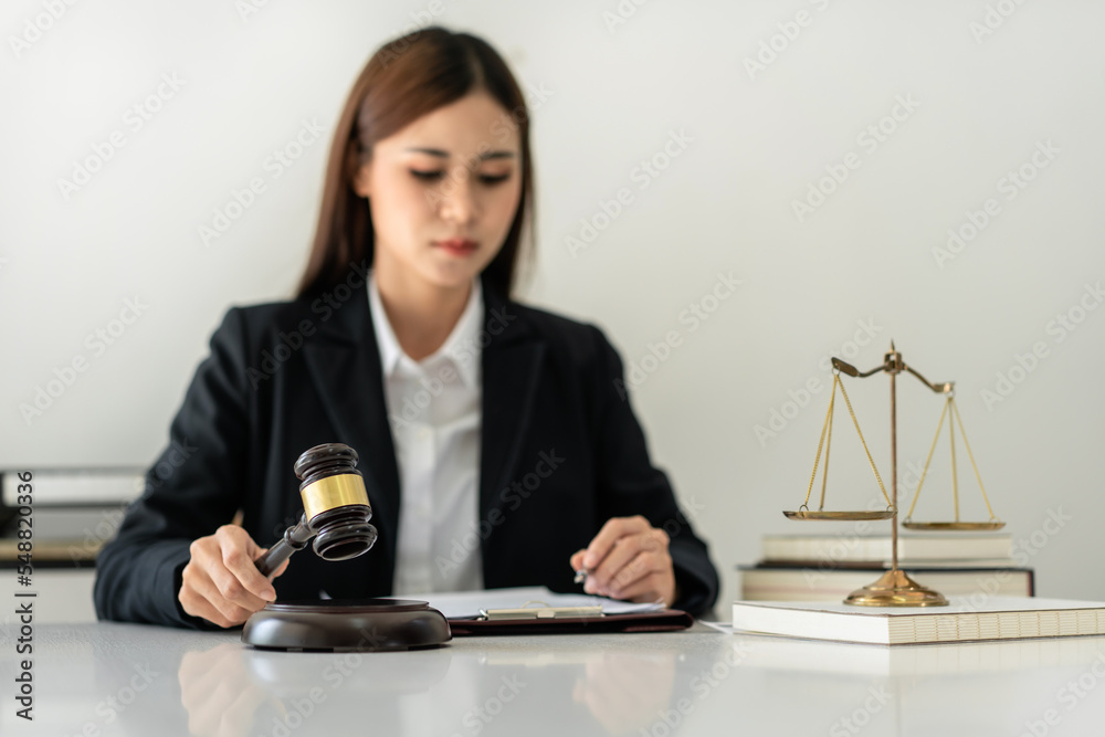 Business lawyer woman holding justice hammer and reading business contract to writing information on document Business lawyer woman holding justice hammer and reading business contract to writing information on document