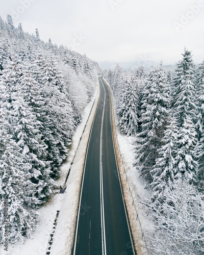 Photo from the drone. Winter landscape. Mountain winding road in a dense snow-covered forest.
