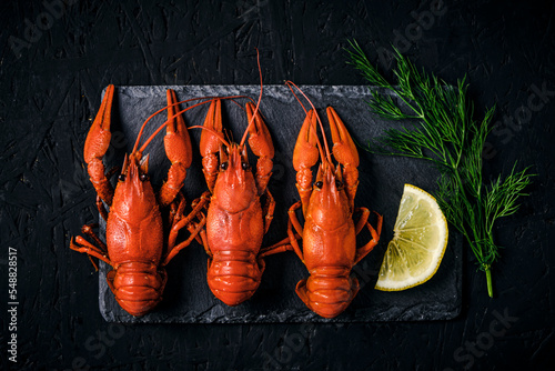Boiled river crayfish with lemon and dillon slate board and dark background.