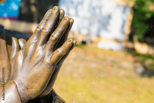 The hands of a praying Tibetan monk or Christian priest  an element of a bronze monument. Background  selective focus