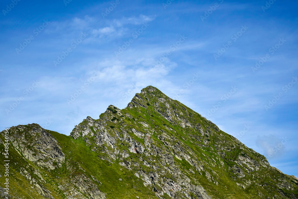 Mountain landscape, peak of mountain range. Close-up. Top of mountain range against blue sky with clouds. Low angle view. Copy space.