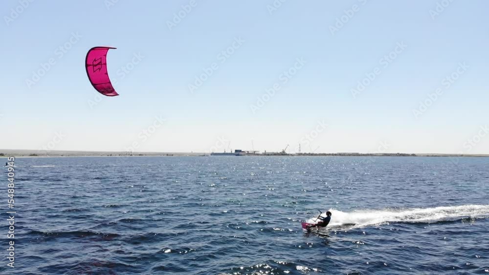 Aerial view of a young caucasian sportswoman cruising on her kitesurf in the open sea on a sunny day