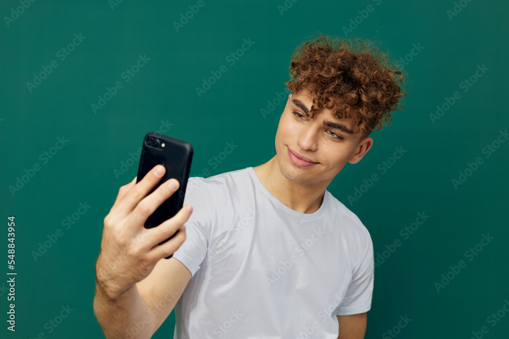 a handsome, joyful man takes a selfie on his phone, smiling pleasantly, standing on a green background a handsome, joyful man takes a selfie on his phone, smiling pleasantly, standing on a green background