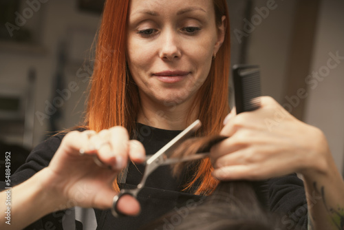 Hairstylist does cutting hair tips of a female customer in a beauty salon. Womens fashion and style. Hair care, beauty industry concept. Hairdresser doing haircut closeup of work
