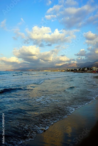 Evening on the shores of the Aegean Sea. Mid October. The magic of nature. The island of Crete. Bright light and low beautiful clouds in the rays of the setting sun.